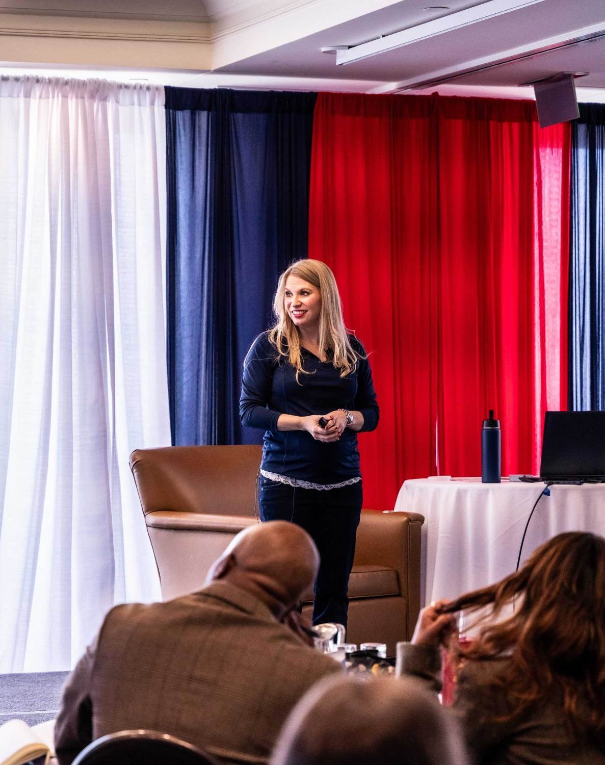 Woman presenting on stage to a seated audience at a business event