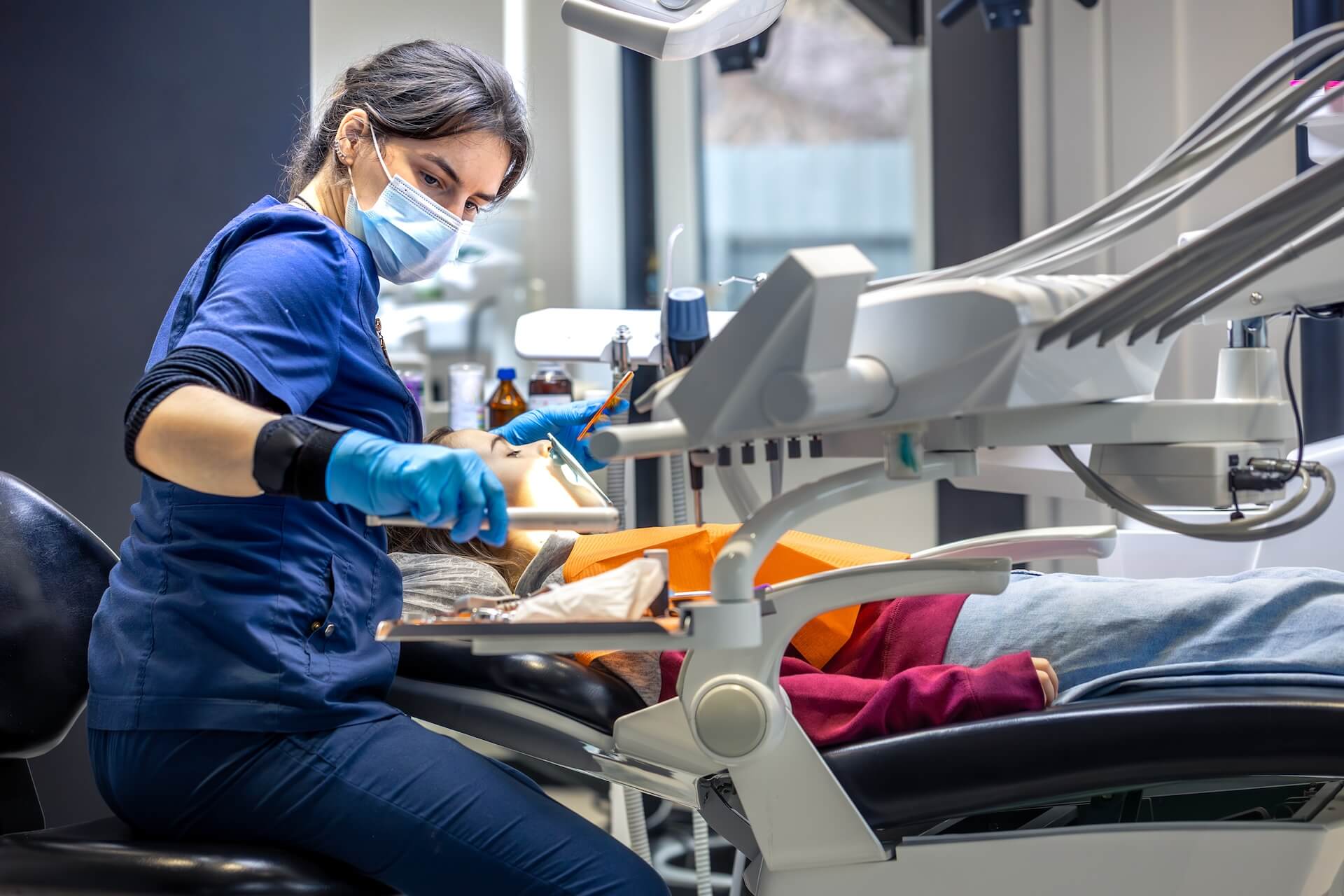 Dental hygienist treating a patient in a treatment room